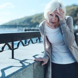 Senior woman feeling dizzy and off balance while out for a walk.