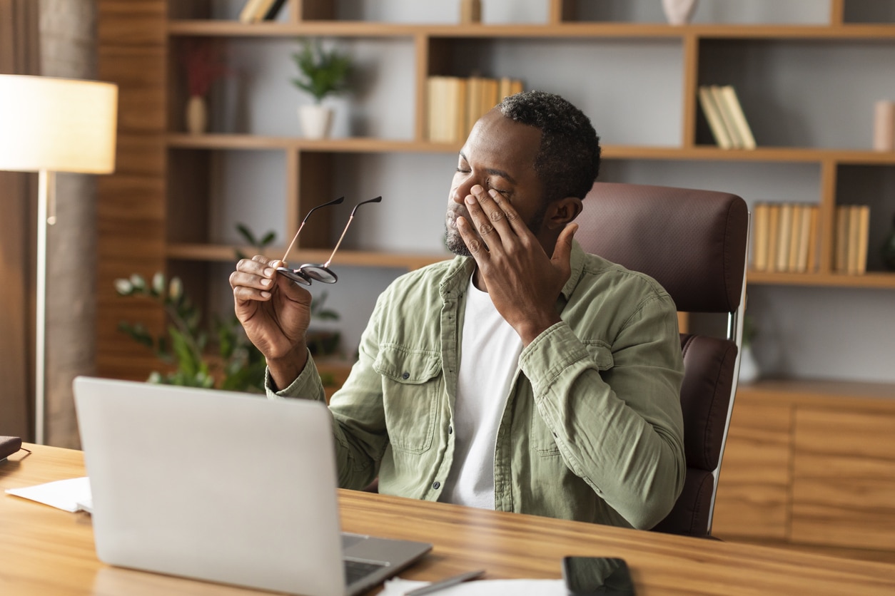 Tired man rubbing his eyes at his computer.